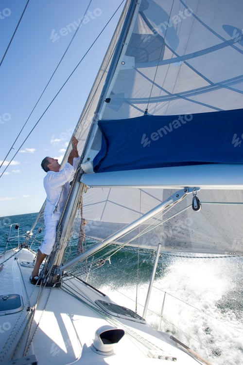 Preview: Senior Man Standing On Deck Of A Yacht Out At Sea And Making Adjustments To The Sail