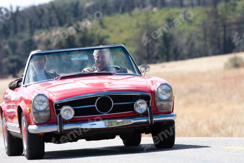 Preview: Horizontal Front View Of A Senior Couple On A Road Trip In A Red Convertible Smiling At The Camera
