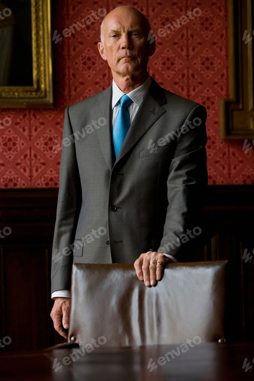 Preview: Portrait Of A Senior Businessman Standing In His Office Behind A Chair With One Hand Placed On The