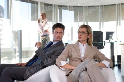 Preview: Horizontal Shot Of A Businessman And Businesswoman In Armchairs In Office With The Man Glaring Over