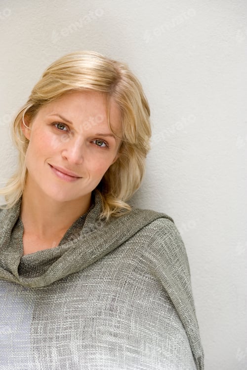Preview: Vertical Portrait Of A Woman Smiling At The Camera In Front Of A White Wall.