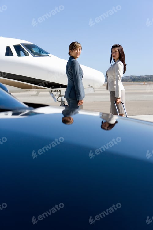Preview: Vertical Shot Of Two Businesswomen By Car And Airplane On A Runway At The Airport.
