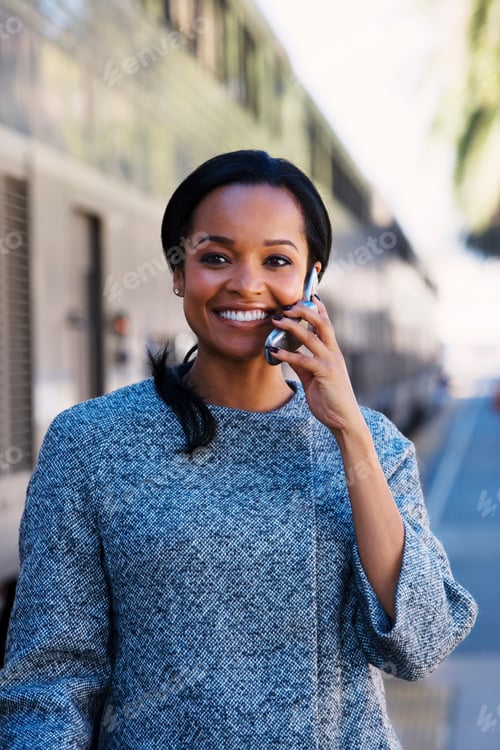 Preview: Horizontal Waist Up Shot Of A Businesswoman Talking On Phone At A Train Station Standing Besides A