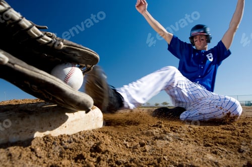 Preview: Surface Level Blurred Motion Image Of A Baseball Player In Blue Uniform Sliding Into A Base On The