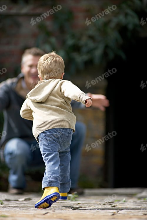 Preview: Selective Focus On A Running Boy In The Foreground Heading Towards His Squatting Father With Open