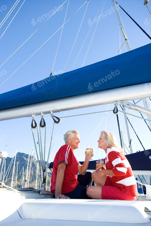 Preview: Vertical Shot Of A Senior Couple Sitting On The Deck Of A Yacht Moored At The Harbor And Drinking
