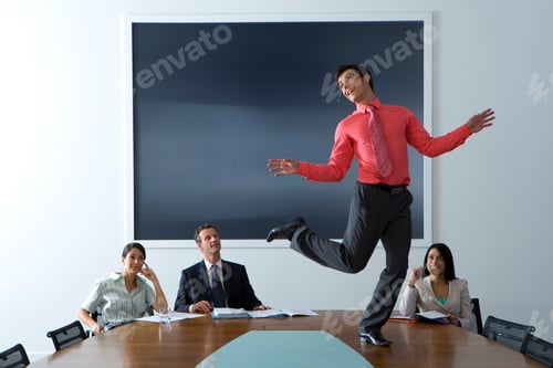 Preview: Horizontal Shot Of A Young Businessman Dancing On A Boardroom Table Watched By His Smiling