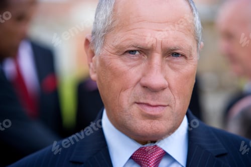 Preview: Headshot Of A Senior Businessman Looking Confidently At The Camera With His Colleagues Standing And
