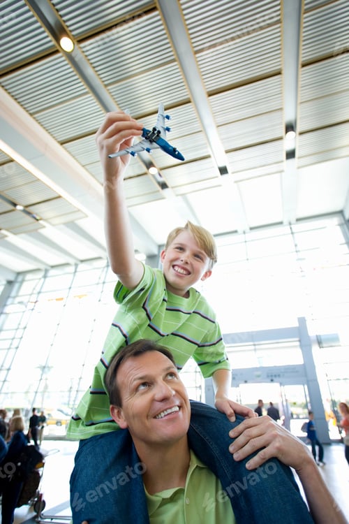 Preview: Father Carrying Son On Shoulder In An Airport Lounge With A Boy Holding A Toy Airplane.