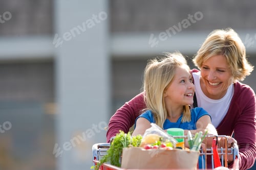 Preview: Horizontal Waist Up Shot Of A Joyous Mother And Daughter Pushing A Grocery Cart Full Of Groceries