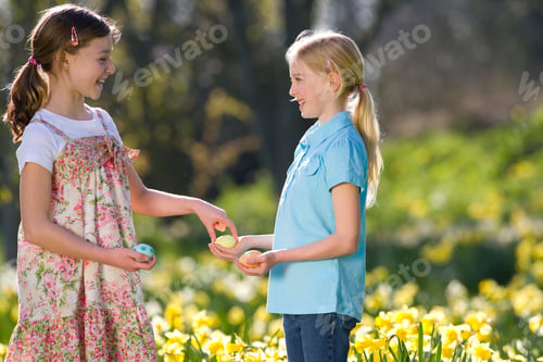 Preview: Horizontal Shot Of Two Young Girls Holding Decorated Easter Eggs In The Field Of Daffodils.