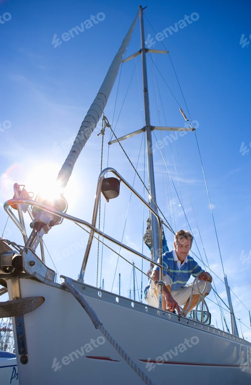Preview: Vertical Shot Of A Young Man Crouching And Holding The Rope On A Deck Of A Moored Sailing Boat.