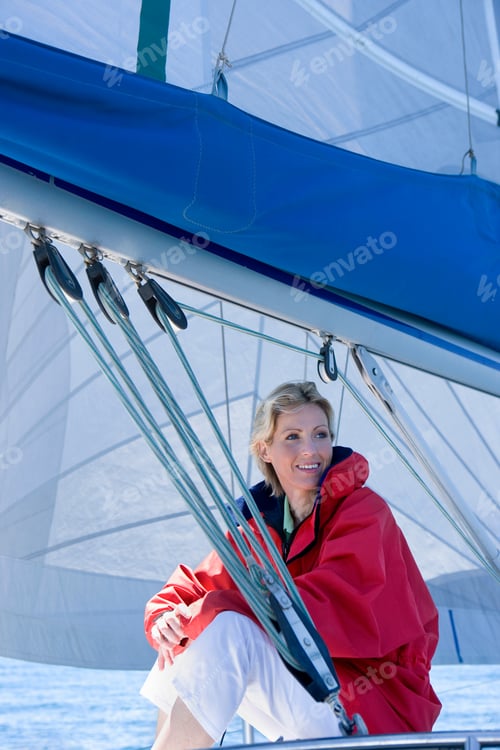 Preview: Close-Up Shot Of A Mature Woman In Red Jacket Sitting On The Deck Of The Sailing Boat Below Sail,