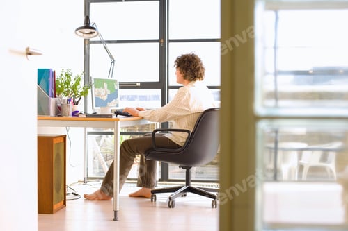 Preview: Horizontal Shot Of A Young Man Sitting On A Chair At His Desk And Looking At A Map On His Computer