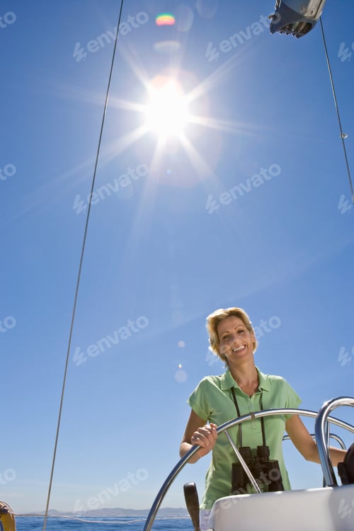 Preview: Vertical Waist Up Shot Of An Enthusiastic Senior Woman Steering A Boat On A Clear Day Smiles At The