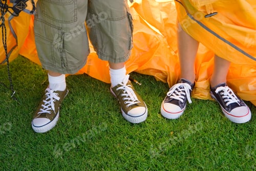 Preview: Horizontal Shot Of Lower Section Of A Brother And Sister Assembling A Dome Tent In The Garden Lawn