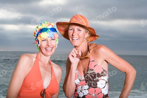 Preview: Close-Up Portrait Of A Mature Woman In Swimming Cap By A Friend In Sunhat On The Beach.