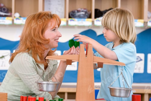 Preview: Teacher Playing With A Little Boy At Nursery School As He Is Trying To Balance A Scale With Weights