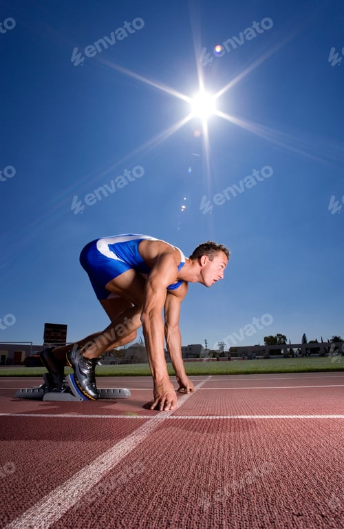 Preview: Side View Of A Young Male Athlete On Starting Blocks Getting Ready To Sprint Down The Track At An