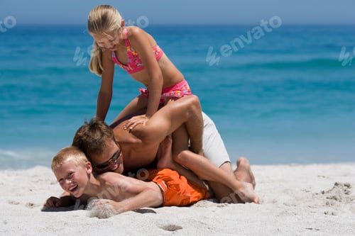 Preview: Father Play Fight With His Two Children On A Sandy Beach On A Sunny Day.