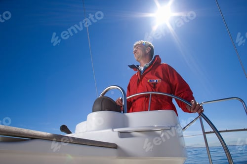 Preview: Horizontal Low Angle View Of Man In Red Jacket Standing And Smiling At The Helm Of A Sailing Boat