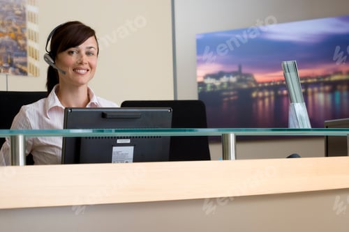 Preview: Waist Up Portrait Of A Receptionist Seated Behind A Counter Smiling At The Camera With Copy Space.