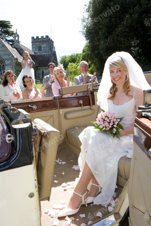 Preview: Wedding Party Cheering By The Seated Bride In A Convertible Vintage Car Smiles At The Camera
