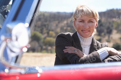 Preview: Horizontal Portrait Of A Senior Woman Sitting Crossed Arms In A Red Convertible Car Smiles At The