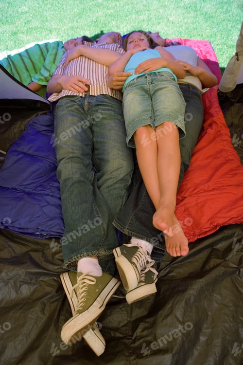 Preview: Vertical Elevated Shot Of A Couple Sleeping Side By Side With Their Daughter Over Sleeping Bags In