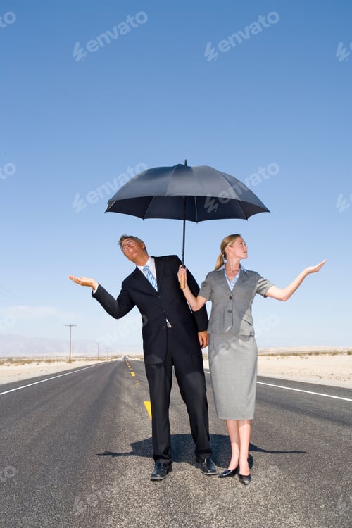 Preview: Vertical Shot Of A Businessman And Woman Feeling For Rain On An Open Road In The Desert With An
