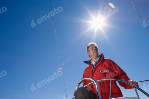 Preview: Low Angle View Of A Man In Red Jacket Standing At The Helm Of Sailing Boat Out At Sea.