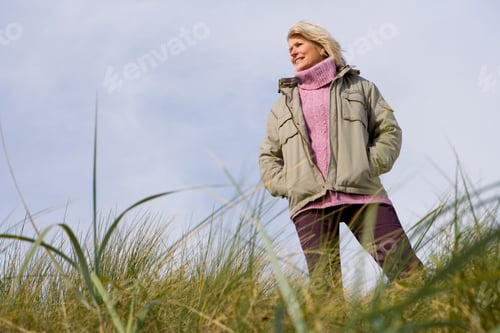 Preview: Portrait Of A Senior Woman Standing On A Grassy Bank On A Bright, Sunny Day Out In The Field
