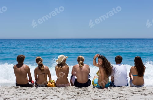Preview: Horizontal Rear View Of A Group Of Teenagers Sitting In Line On The Beach Looking At The Horizon