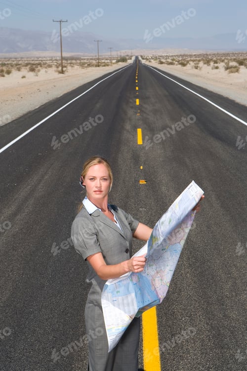 Preview: Vertical Shot Of A Businesswoman With A Road Map In The Middle Of An Open Road In The Desert.