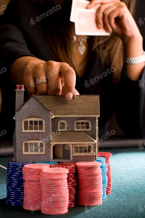 Preview: Vertical Close Up Of A Woman Placing A Model House On A Pile Of Gambling Chips On The Table During