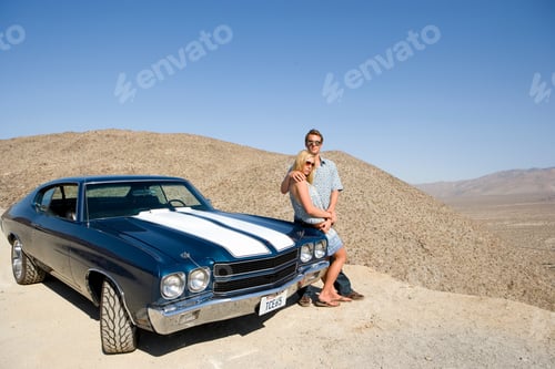 Preview: Elevated View Of A Young Couple Leaning On The Car And Looking At The View In The Desert.