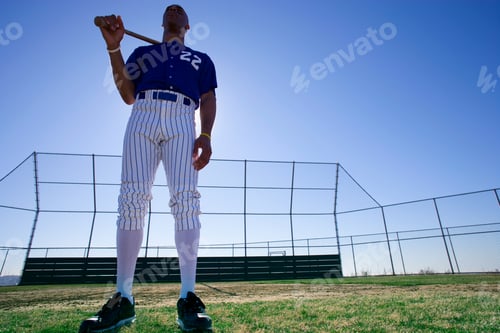 Preview: Low Angle Portrait Of A Baseball Batter Wearing Number 22 Blue Uniform Standing On The Pitch With