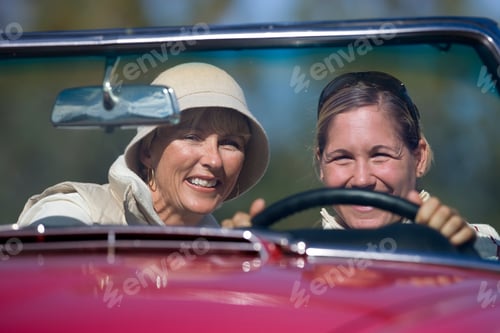 Preview: Front View Of Two Joyous Women Driving In An Red Convertible On A Sunny Day.