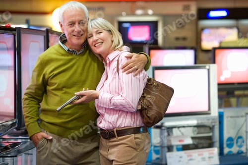 Preview: Senior Couple Hugging In The Middle Of An Electronics Appliances Store And Shopping For A New