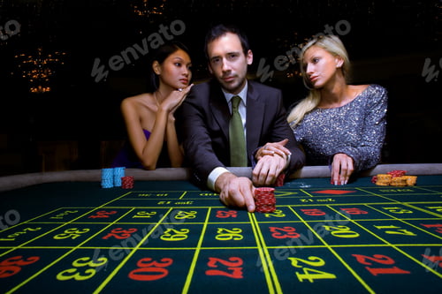 Preview: Portrait Of A Gambler Man Flanked By Two Women Pushing His Chips Forward On The Roulette Table.