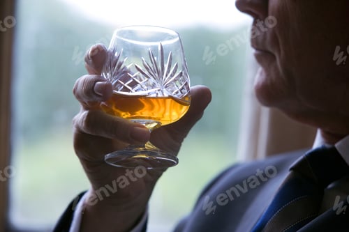 Preview: Close Up Of A Senior Businessman Sitting On A Chair In His Office Next To A Window Holding A Glass