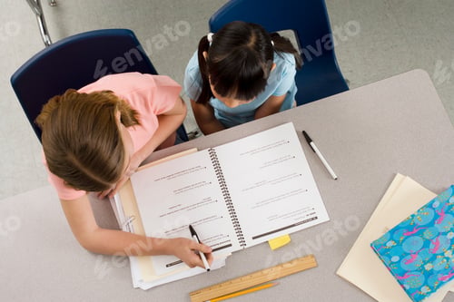 Preview: Horizontal Overhead Shot Of Two Girls Studying On A Desk In A Classroom.