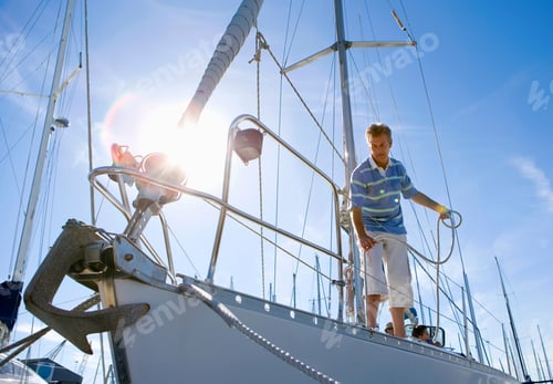 Preview: Horizontal Shot Of A Young Man Standing And Holding The Rope On Deck Of A Moored Sailing Boat.