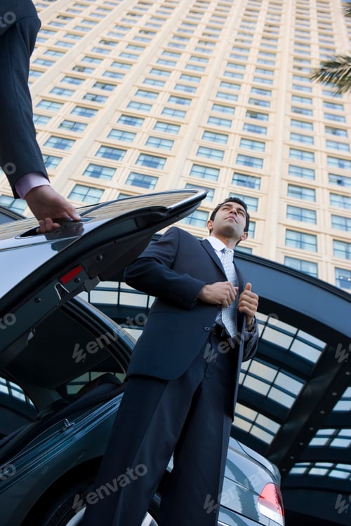 Preview: Low Angle Shot Of A Businessman Adjusting His Suit Upon Exiting A Car In Front Of A High-Rise.