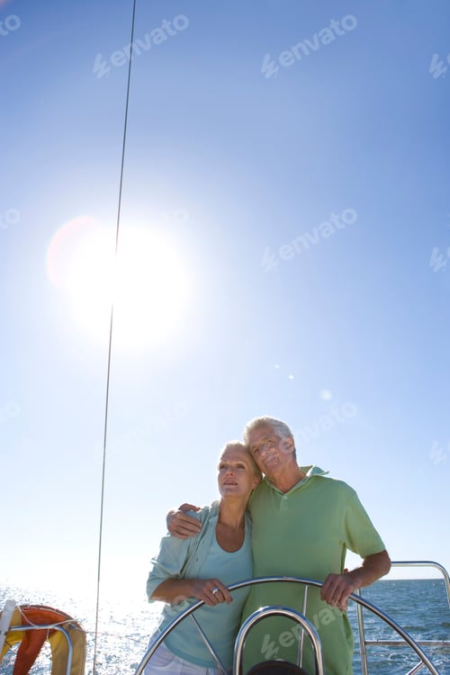 Preview: Vertical Shot Of A Senior Couple Standing At The Helm Of A Yacht Out At Sea With Their Arms Around
