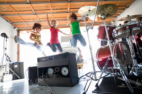 Preview: Horizontal Low Angle Shot Of Three Joyous Teenage Girls Leaping In Air By The Drum Kit And