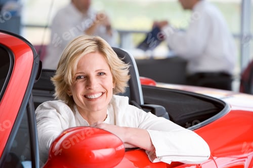 Preview: Horizontal Shot Of A Woman Sitting In A Red Convertible Smiles At The Camera With A Salesman
