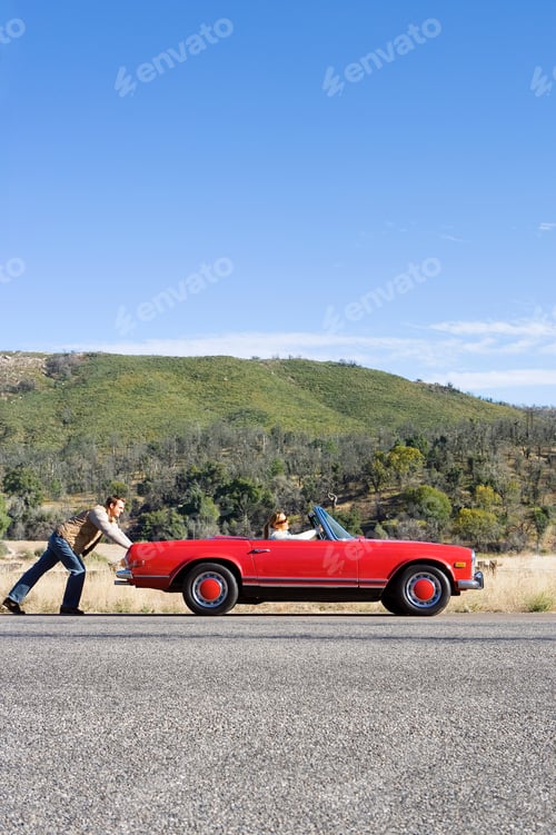 Preview: Vertical Profile Shot Of A Young Man Pushing A Car Having Trouble With His Girlfriend At The Wheel