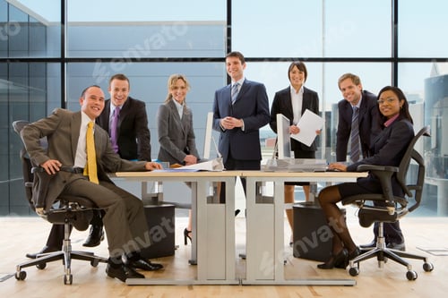 Preview: Group Of Business People Standing Around The Desk And Looking At The Camera With A Smile On Their