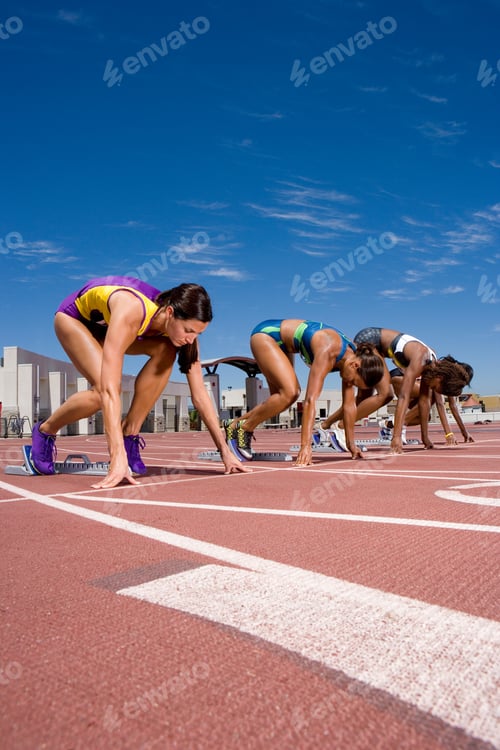 Preview: Vertical Shot Of Young Female Runners At Their Starting Blocks Waiting For The Race Start At An